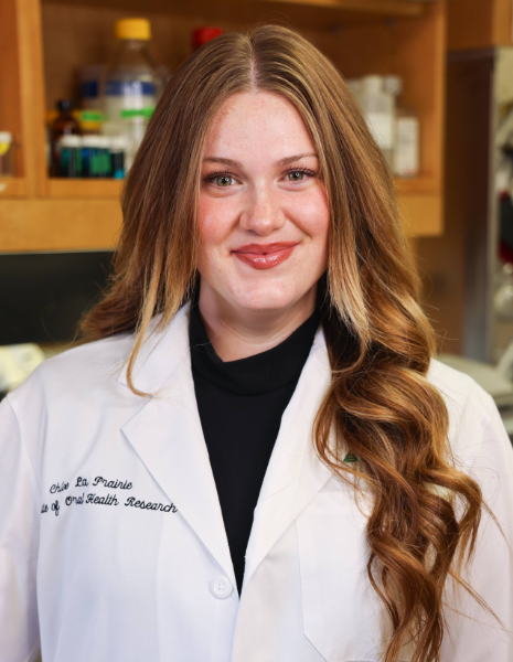 Woman with dirty blonde hair wearing a white coat smiling in a lab setting